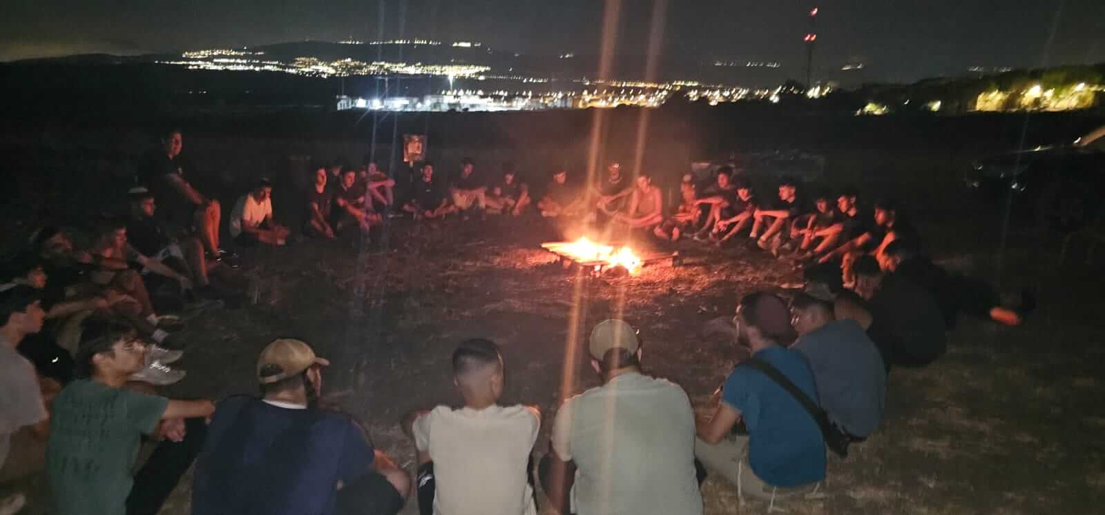 חניכי תמיר יושבים יחד סביב מדורה בערב מחזור